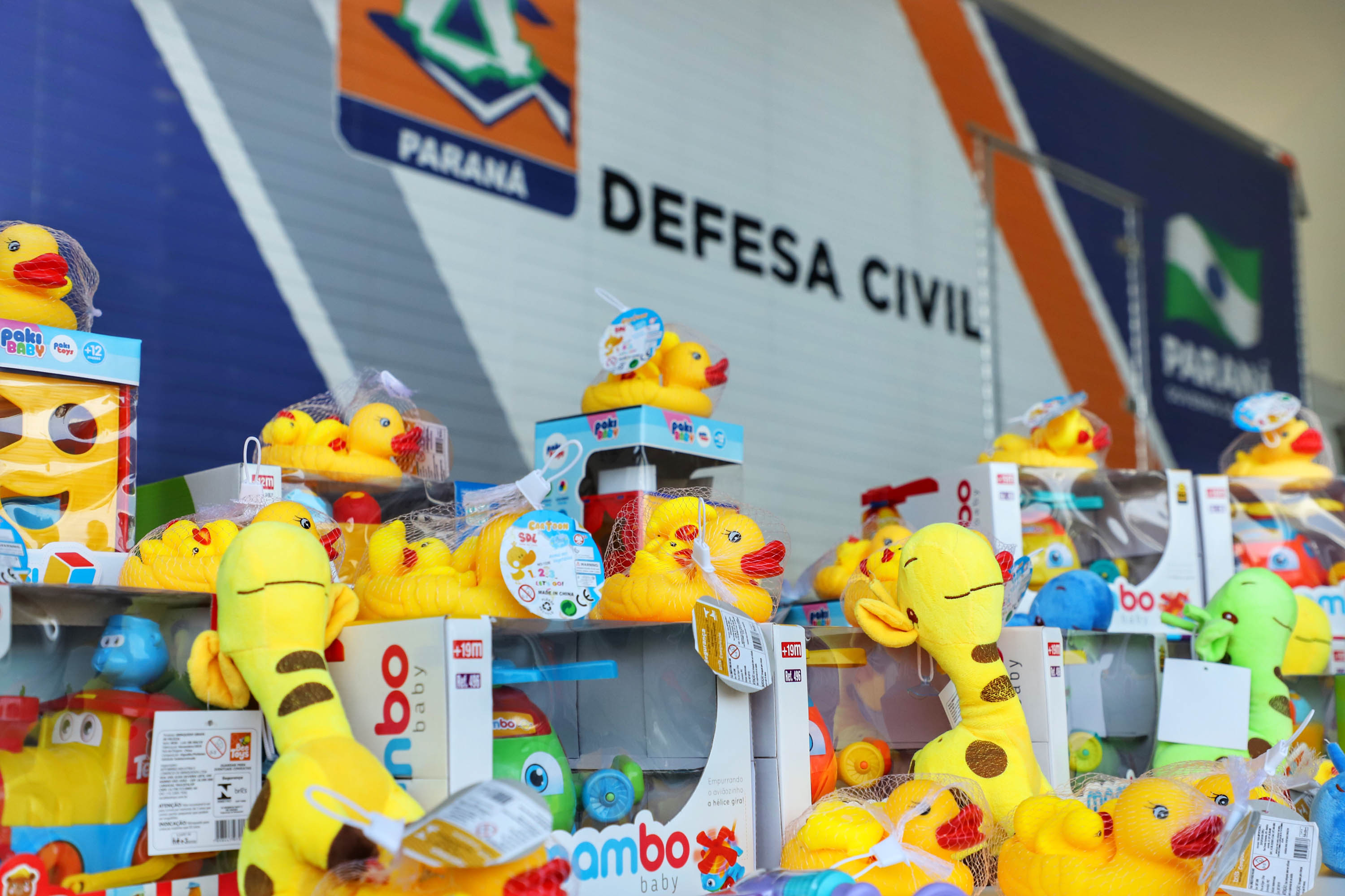 Pilha de brinquedos em frente ao caminhão da Defesa Civil do Paraná